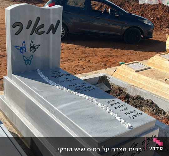 מצבה עם כיתוב בעברית ופרפרים צבעוניים